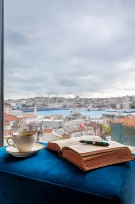 a book and a cup of coffee and a pen on a table at Union Hotel Karaköy in Istanbul