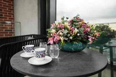 a table with two cups and a vase with flowers at The Mill Bomonti in Istanbul