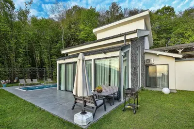 a patio with a table and an umbrella next to a house at New Balturk Villas Sapanca in Sapanca