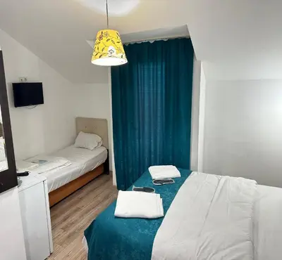 a small room with two beds and a blue curtain at Taksim Soushian Hotel in Istanbul