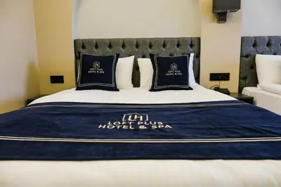 a bed with a blue and white blanket and pillows at Plus Hotel & Private Transportation İstanbul Airport-By Loft in Arnavutköy