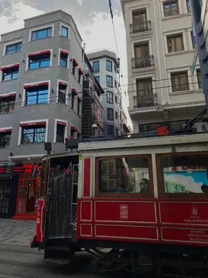 a red trolley car on a city street with buildings at Li Hotel Pera in Istanbul