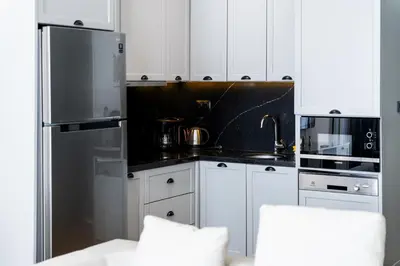 a kitchen with white cabinets and a stainless steel refrigerator at DeCamondo Residence in Istanbul