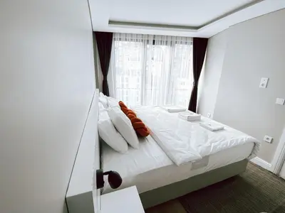 a bedroom with a bed with white sheets and a window at Bolahenk Suites in Istanbul