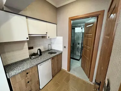 a small kitchen with white cabinets and a sink at H&L Suites in Istanbul