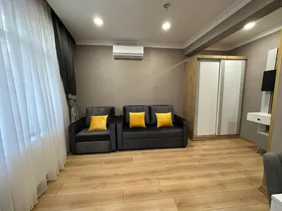 a living room with a black couch and yellow pillows at H&L Suites in Istanbul