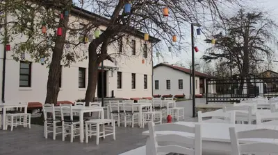 a group of white tables and chairs in front of a building at İstasyon Otel in Boyalık
