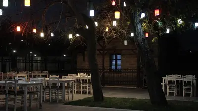 a group of tables and chairs in a courtyard at night at İstasyon Otel in Boyalık