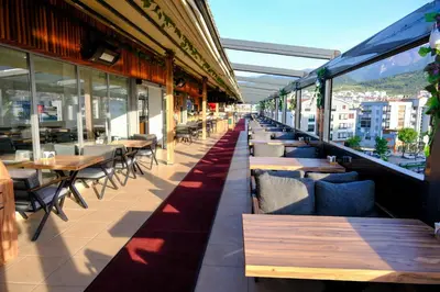 a restaurant with tables and chairs on a balcony at Velmore Hotel & Spa in Kestel