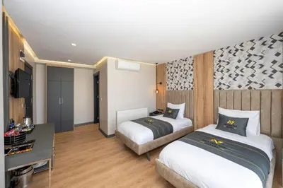 a hotel room with two beds and a desk at Heaven Inn Airport Hotel in Arnavutköy
