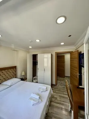 a bedroom with a large white bed and a desk at EYFEL HOTEL in Istanbul