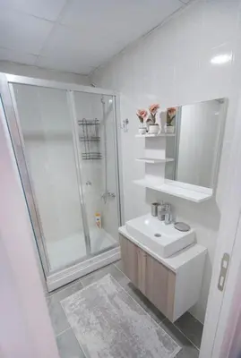 a white bathroom with a sink and a shower at Two Bedroom King Deluxe Suite IS9 in Esenyurt