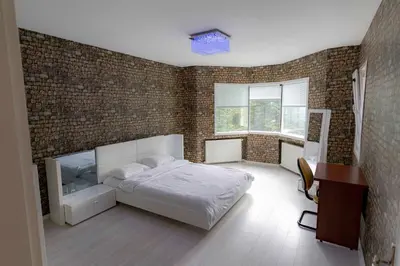 a bedroom with a white bed and a brick wall at Bungalov Maşukiye Villa in Kartepe
