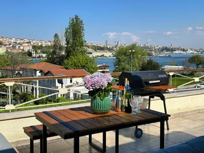 a table with flowers and a grill on a balcony at Waterfront Apartment by the Tram - Terrace with Dome & Golden Horn View in Fatih in Istanbul