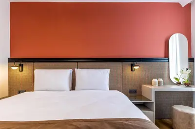a bedroom with a white bed with an orange wall at BayMari Suites City Life in Istanbul