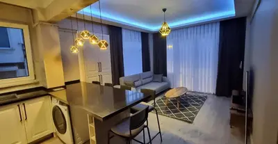 a kitchen and living room with a table and chairs at Tam Merkezde Yepyeni Bir Daire in Istanbul
