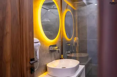 a bathroom with a white sink and a round mirror at Parla Suite Hotel in Esenyurt