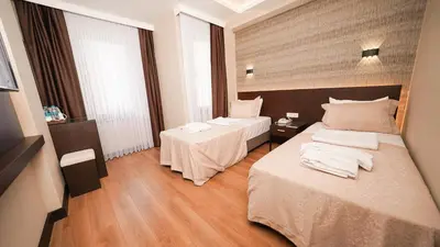 a hotel room with two beds and two tables at Bellezza Hotel in Istanbul