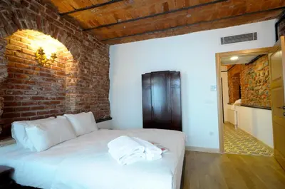 a bedroom with a white bed with a brick wall at Casa 1899 in Istanbul