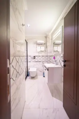 a white bathroom with a toilet and a sink at Garden Room Suit Hotel in Istanbul
