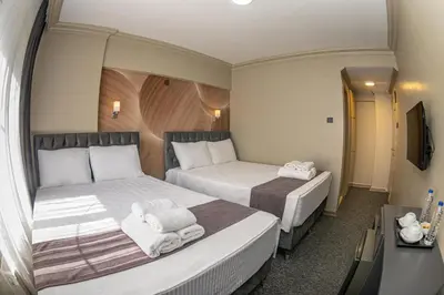 two beds in a small room with a tv at BURSA LOYAL CiTY HOTEL in Bursa