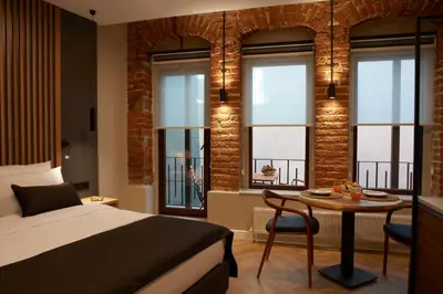 a bedroom with a bed and a table and windows at CASA GALATA 35 in Istanbul
