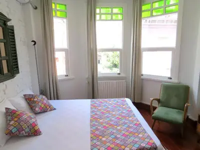 a bedroom with a bed and a chair and windows at Istanberry - Luna Apartments in Istanbul